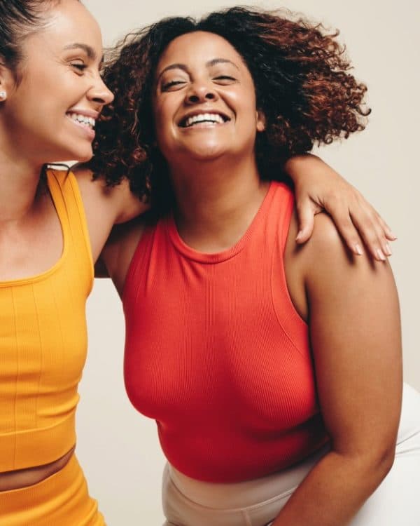 3 women in sportswear embracing each other and smiling