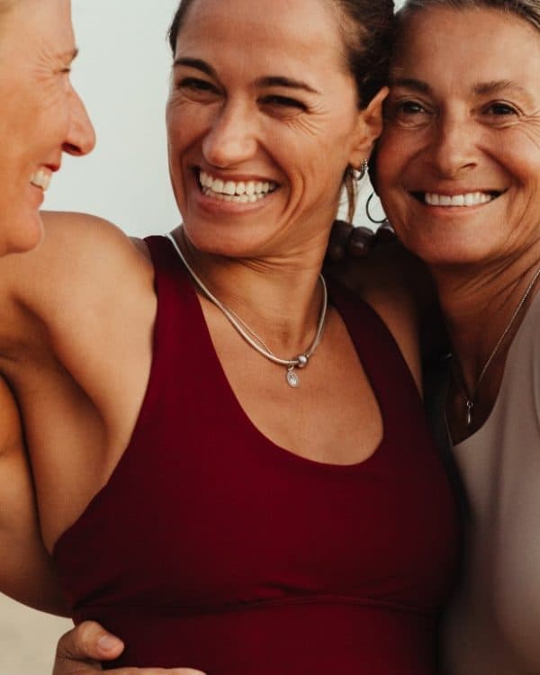 3 women in sportswear embracing each other and smiling